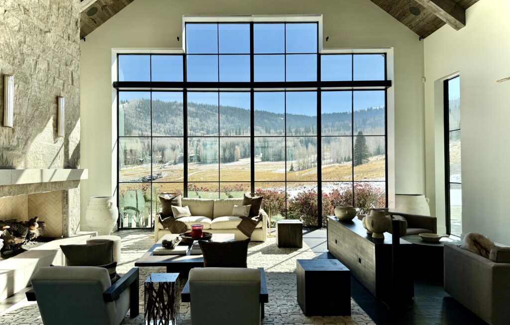 Modern luxury custom home setting, living room, with panoramic views of the Utah mountains, winter landscape, green winter forest.