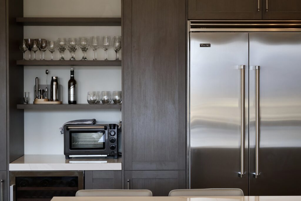European cabinetry kitchen with slim shaker cabinets, frameless European cabinetry, phantom shaker cabinet doors, custom European kitchen design, modern shaker cabinetry, luxury custom cabinetry Utah, European style kitchen cabinets, custom frameless cabinets, custom shaker kitchen park city utah, two tone kitchen cabinets white oak and dark brown, bertazzoni heritage range custom cabinetry, built in fridge cabinets park city kitchen, shaker kitchen with glass cabinets and open shelves, custom kitchen island with seating and storage, modern shaker kitchen design park city utah, kitchen bar area with wine fridge and shelving, frameless shaker cabinets with blum hardware, custom bathroom vanity rustic white oak cabinets