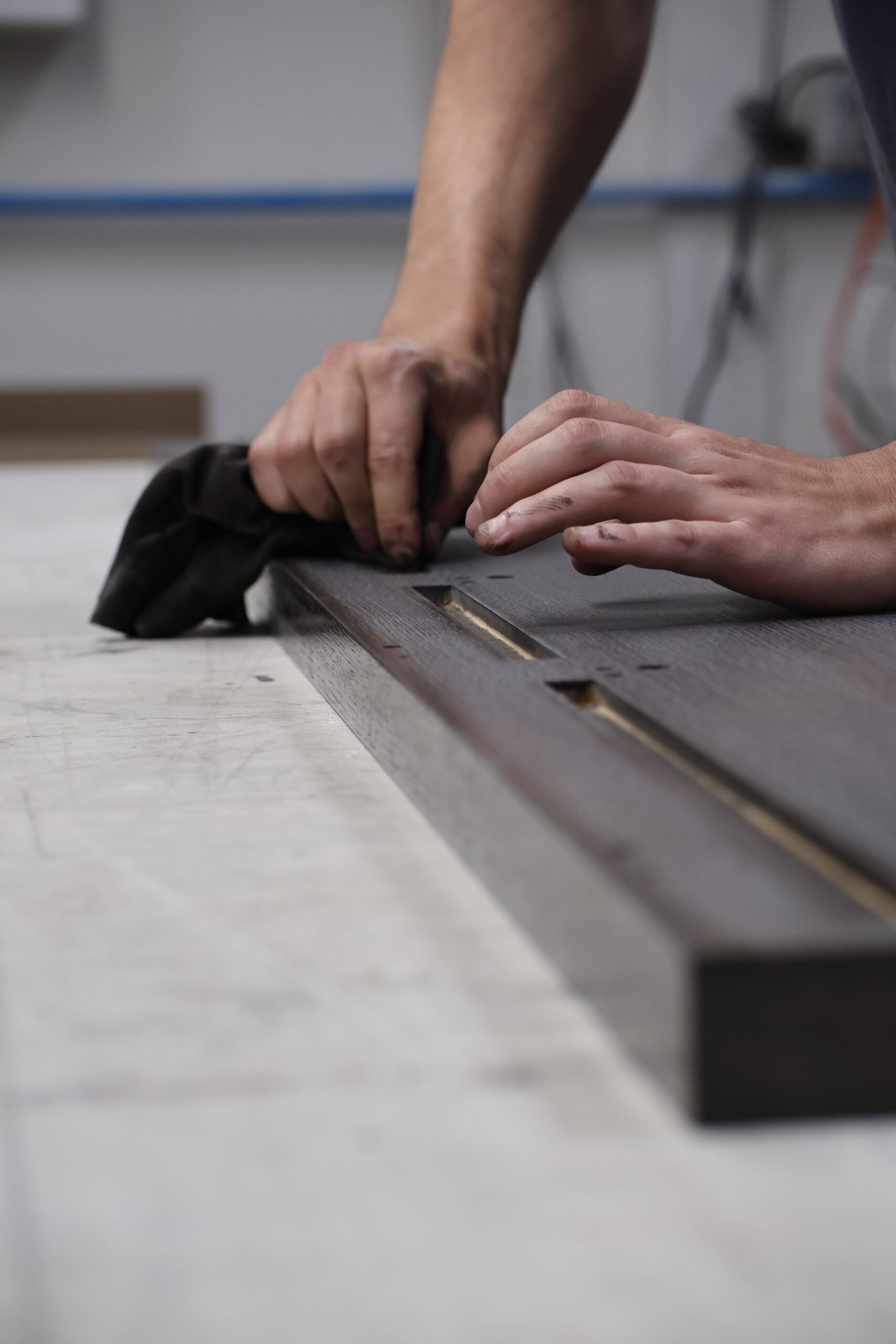 Custom cabinetry finishing process in professional spray and stain shop, Woodworker preparing cabinet surfaces for high-end finishing, Sanding process for luxury custom cabinetry components, Stained wood cabinetry panels in Utah finishing workshop, Professional cabinet finishing environment with controlled spray booth
