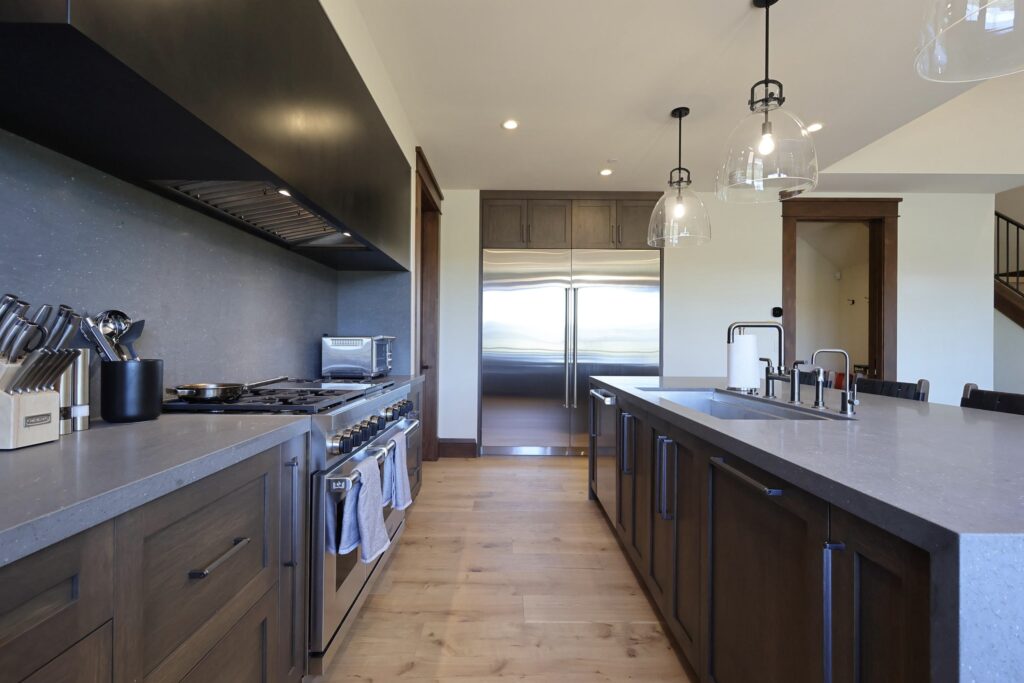 Utah custom cabinets kitchen design luxury kitchen planning process custom cabinet storage solutions European cabinetry kitchen layout frameless Utah custom cabinets luxury kitchen workflow design, victory ranch custom shaker kitchen dark wood veneer cabinetry, luxury mountain home kitchen with custom stained shaker cabinets and large island, custom bar area victory ranch home with dark cabinetry and open shelving, wolf range with custom shaker cabinetry and oversized vent hood, luxury pantry cabinetry with natural wood veneer and custom stain, mountain modern kitchen cabinetry in victory ranch utah, custom kitchen island with waterfall seating and dark stained cabinetry, shaker style cabinetry with wide access sink cabinet doors, custom tray pull out storage cabinetry victory ranch kitchen, luxury custom cabinets park city and victory ranch homes